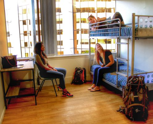 Image of a 4 bed dorm showing 3 people sitting and lying on bunk beds