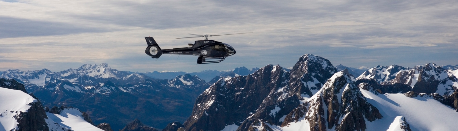 Helicopter flying over snow covered mountains
