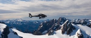 Helicopter flying over snow covered mountains